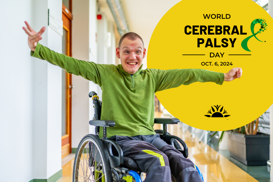 Male with cerebral palsy in a wheelchair wearing a green sweater with his arms out smiling. Yellow circle with the text world cerebral palsy day october 6 2024 with a green ribbon