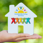 Hand holding ceramic white house with Sunbeam Community Living Services logo and silhouette of five people in rainbow colours